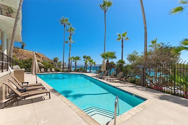 pool featuring a patio area, fence, and a water and mountain view