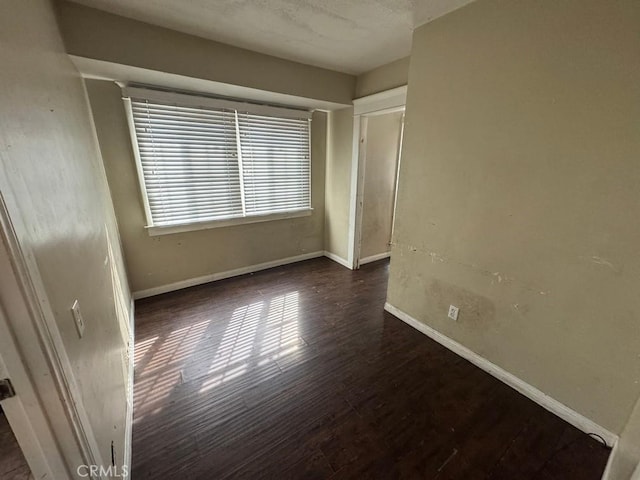 empty room with dark wood-style floors and baseboards