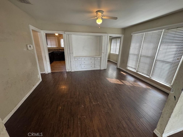 interior space featuring dark wood-style floors, ceiling fan, and baseboards