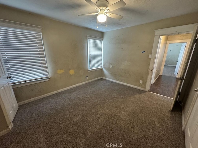 unfurnished bedroom featuring dark carpet, baseboards, and ceiling fan