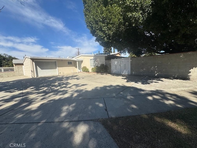 view of front of property featuring a garage, concrete driveway, and a fenced front yard