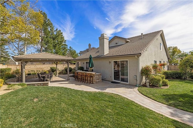 back of property featuring a lawn, a patio, outdoor dry bar, a gazebo, and stucco siding