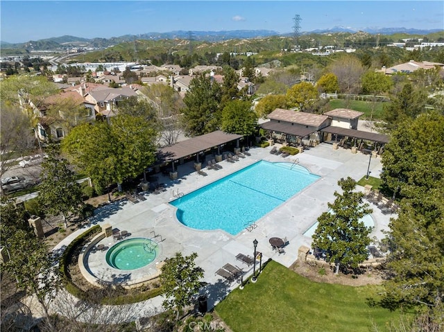 pool with a mountain view, a community hot tub, a patio area, and a residential view