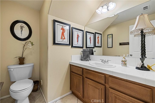 bathroom featuring baseboards, toilet, lofted ceiling, tile patterned floors, and vanity