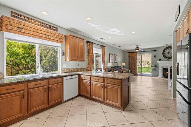 kitchen with open floor plan, freestanding refrigerator, a peninsula, white dishwasher, and a sink