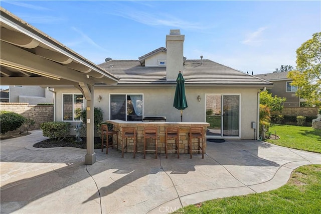 back of house with a patio, a tile roof, fence, outdoor dry bar, and stucco siding