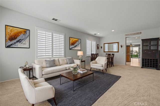 living room with recessed lighting, visible vents, and light colored carpet