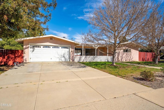 single story home with a garage, fence, concrete driveway, stucco siding, and a front lawn