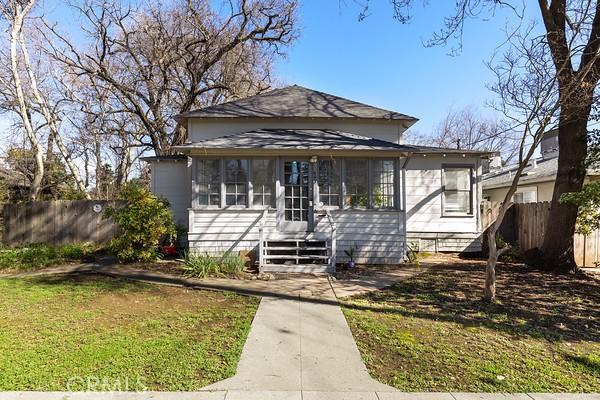 bungalow-style house with a sunroom, fence, and a front yard