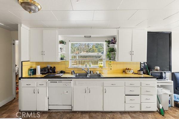 kitchen with a sink, tasteful backsplash, white cabinets, and dishwasher