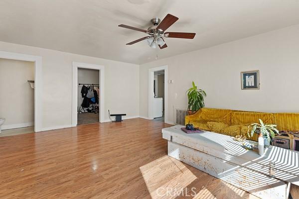 living area with visible vents, wood finished floors, a ceiling fan, and baseboards