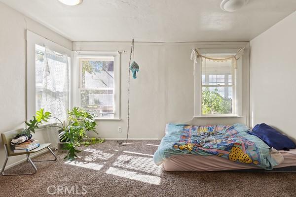 carpeted bedroom featuring multiple windows and baseboards