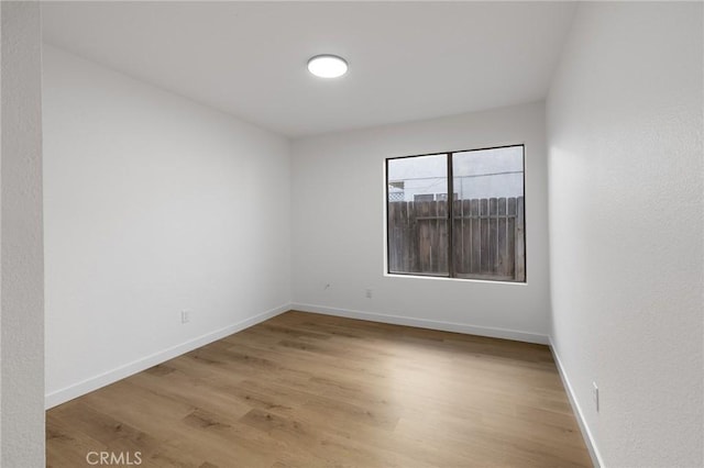 empty room with light wood-type flooring and baseboards