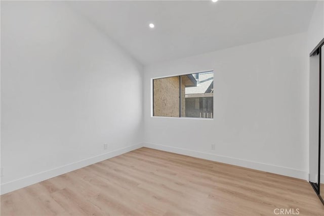 unfurnished room featuring light wood finished floors, baseboards, vaulted ceiling, and recessed lighting