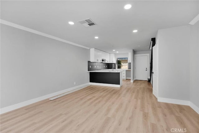 kitchen with light countertops, visible vents, open floor plan, white cabinets, and a peninsula