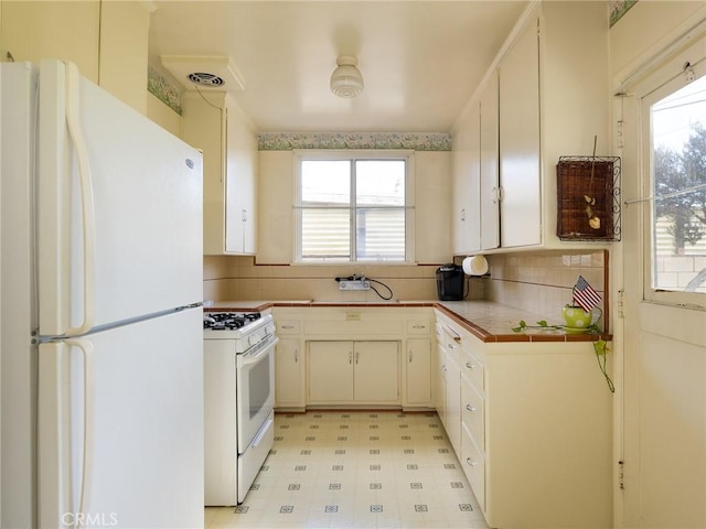 kitchen featuring tasteful backsplash, white appliances, white cabinets, and light floors