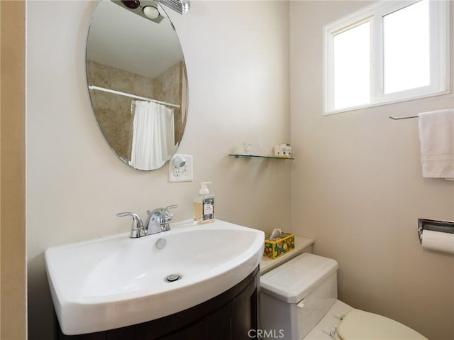 full bathroom featuring tiled shower, vanity, and toilet