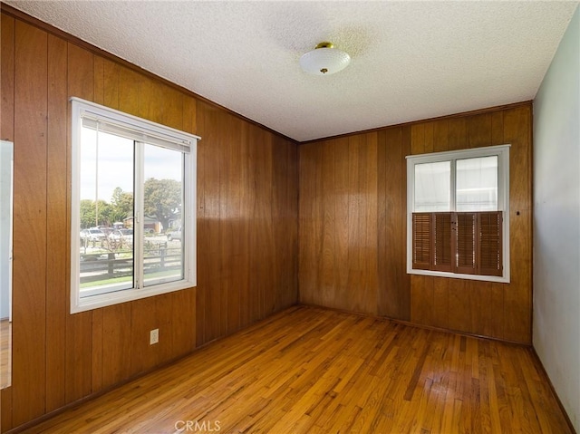 spare room featuring light wood finished floors, a textured ceiling, and wood walls