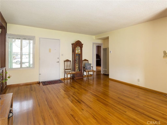 entryway with a textured ceiling, baseboards, and wood finished floors