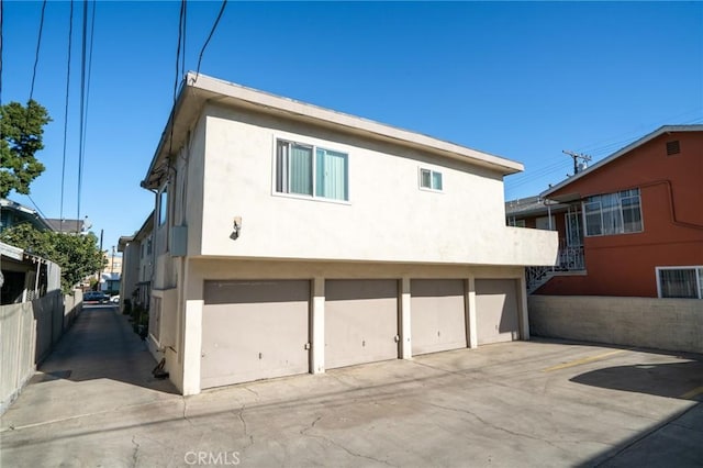 exterior space with a garage, fence, and stucco siding