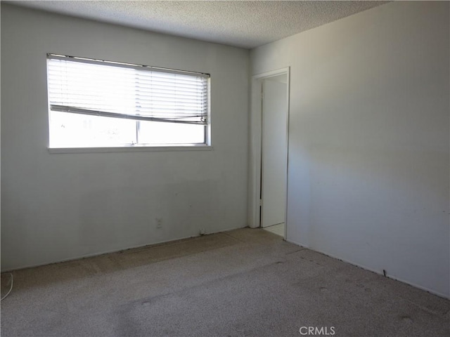 empty room with light carpet and a textured ceiling