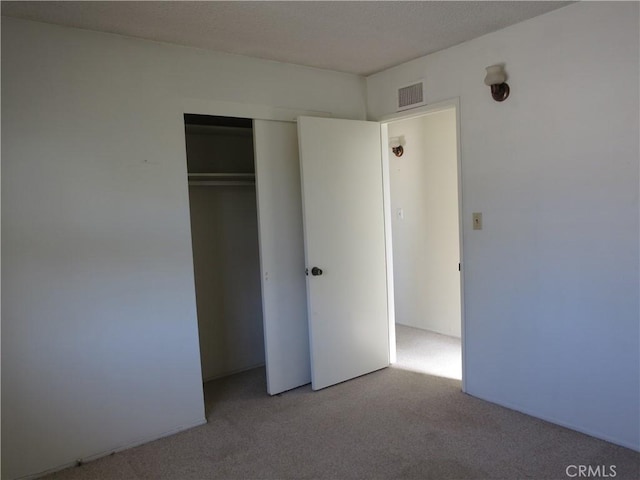 unfurnished bedroom with light colored carpet, a closet, and visible vents