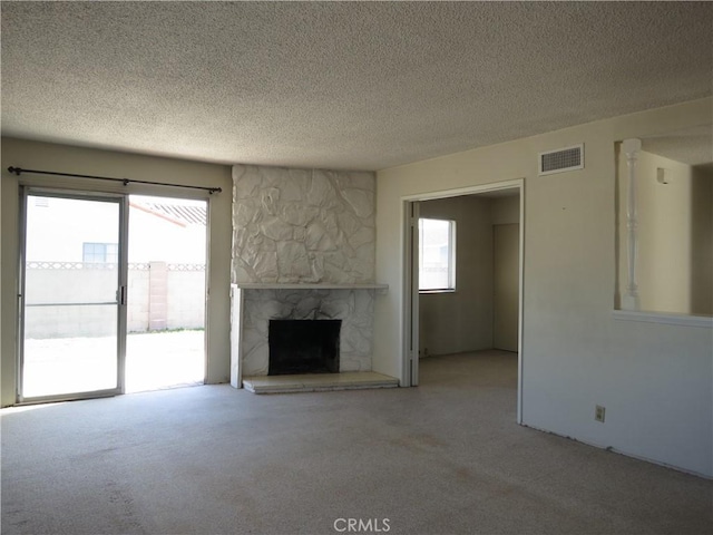 unfurnished living room featuring light carpet, visible vents, a stone fireplace, and a textured ceiling