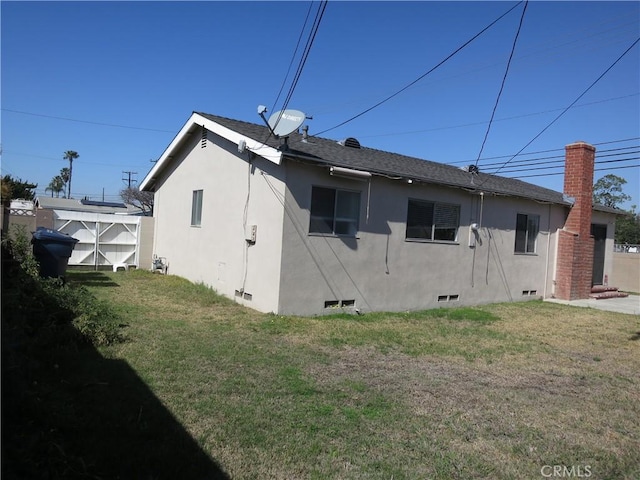 rear view of property featuring crawl space, roof with shingles, a lawn, and stucco siding