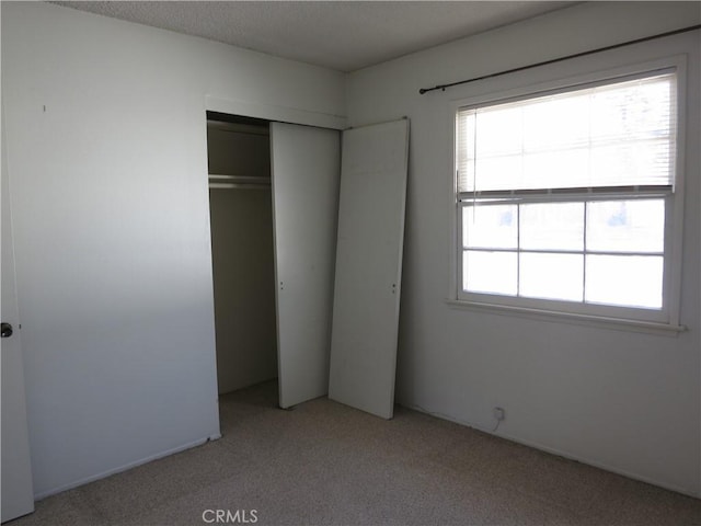 unfurnished bedroom featuring multiple windows, a closet, and light colored carpet