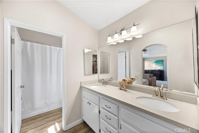 bathroom featuring double vanity, connected bathroom, wood finished floors, and a sink