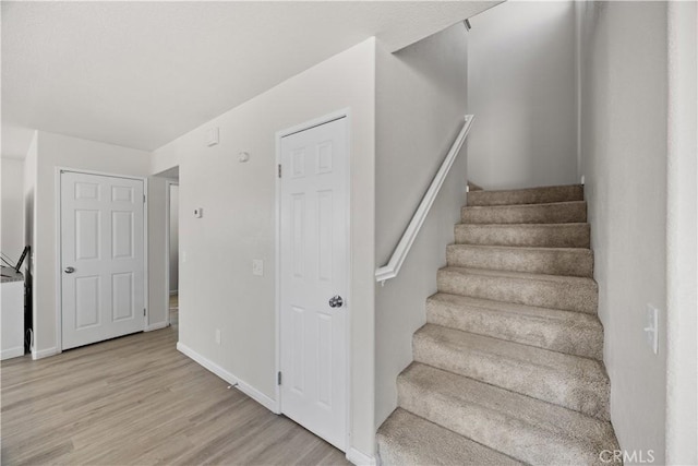 staircase with baseboards and wood finished floors