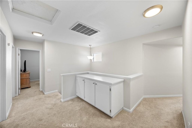 hallway featuring light carpet, visible vents, attic access, and baseboards