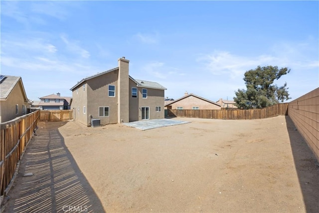 back of house with a patio, central air condition unit, a fenced backyard, and a chimney