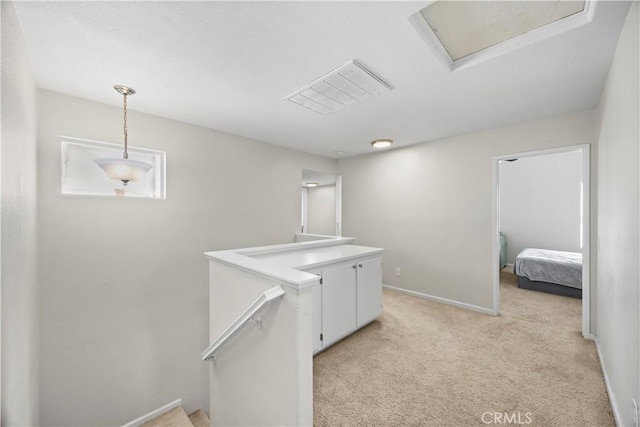 hall featuring visible vents, an upstairs landing, light carpet, baseboards, and attic access