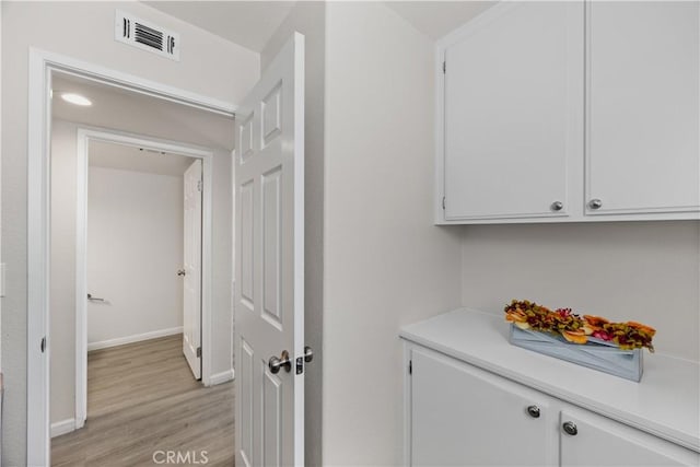 laundry room with baseboards, visible vents, and light wood-type flooring