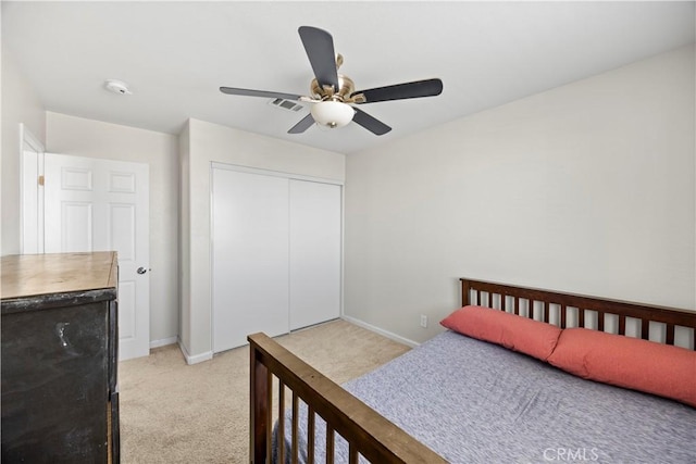 bedroom with baseboards, visible vents, a closet, and light carpet