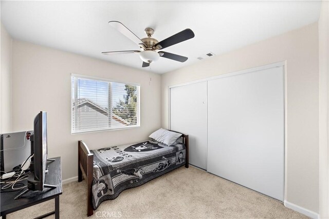 carpeted bedroom with a closet, visible vents, and ceiling fan