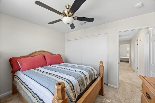 bedroom featuring visible vents, a ceiling fan, a closet, baseboards, and light colored carpet