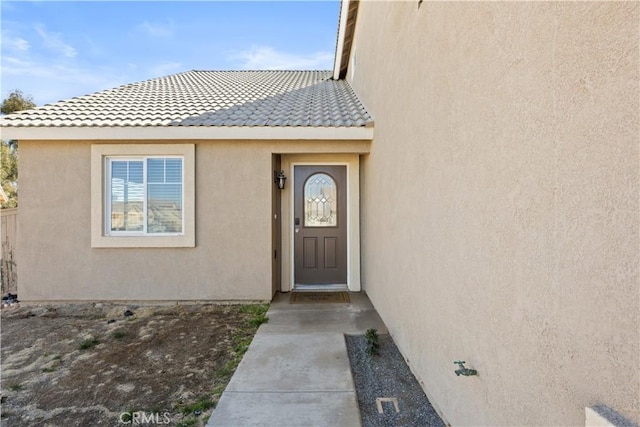 doorway to property with stucco siding and a tiled roof