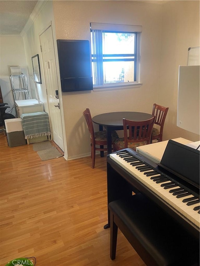 dining room featuring baseboards, ornamental molding, and light wood-style floors