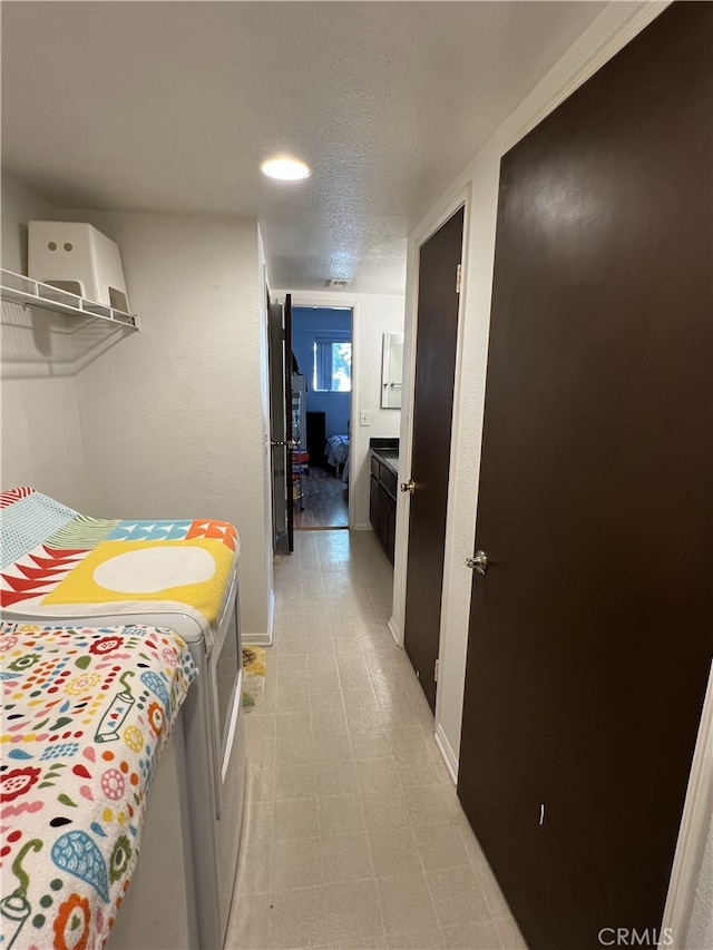 corridor with baseboards, a textured ceiling, and light floors