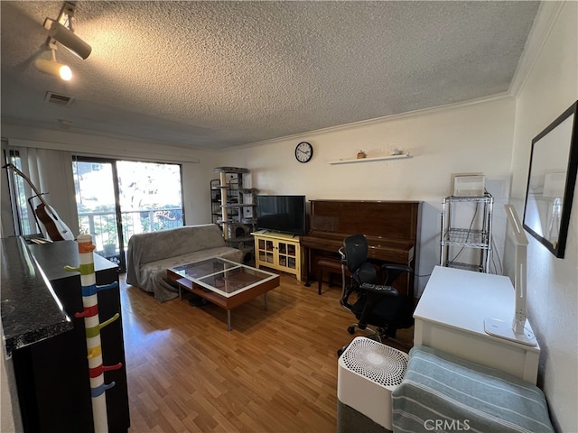 living room featuring visible vents, crown molding, a textured ceiling, and wood finished floors