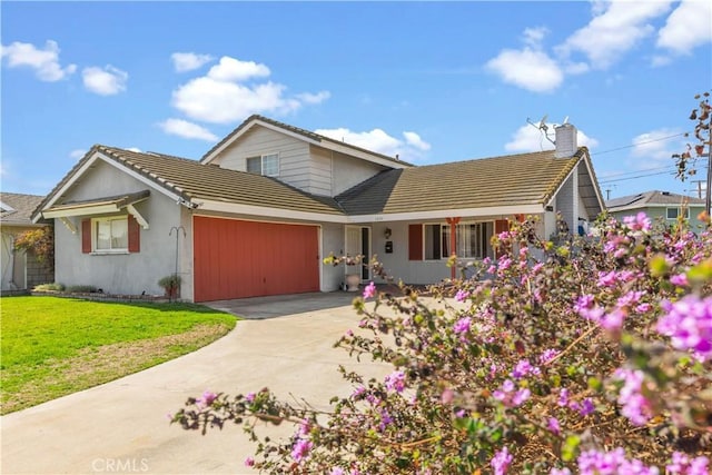 view of front of property with an attached garage, concrete driveway, a tiled roof, a front lawn, and a chimney