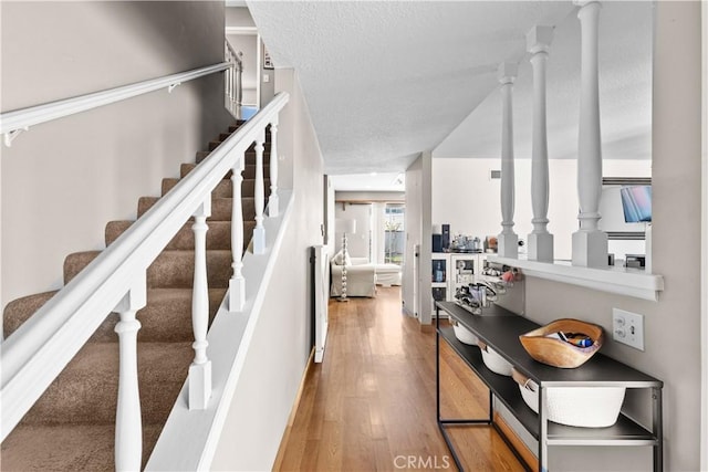 stairway with a textured ceiling and wood finished floors