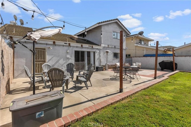 rear view of house with a patio, stucco siding, a lawn, fence, and a tiled roof