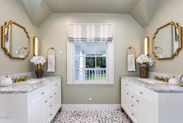 bathroom with vaulted ceiling, two vanities, and a sink