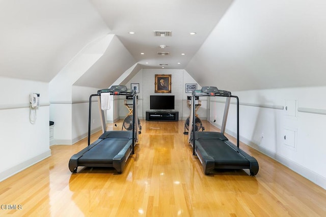 exercise room with visible vents, vaulted ceiling, and wood finished floors