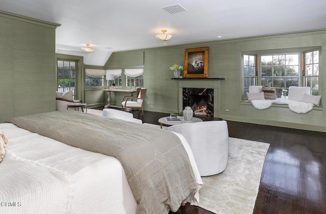 bedroom with dark wood-style flooring, a high end fireplace, visible vents, baseboards, and crown molding