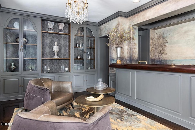 sitting room with ornamental molding, a decorative wall, dark wood finished floors, and a chandelier