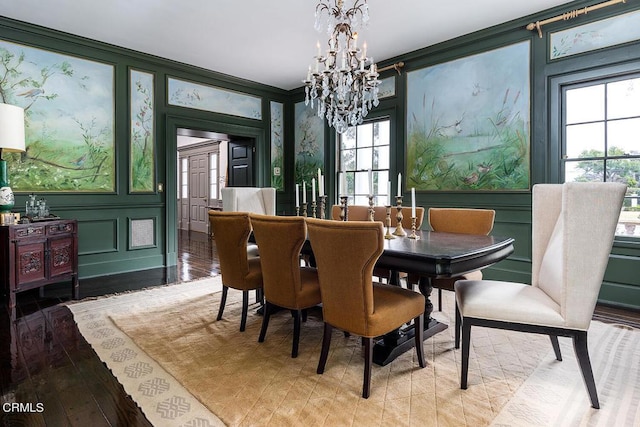 dining room with light wood-type flooring, an inviting chandelier, ornamental molding, and a decorative wall